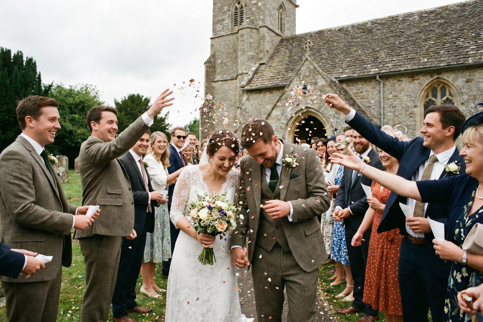 Guests throwing confetti over a couple outside an English country church